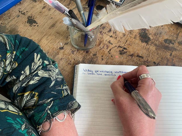 A hand holding a fountain pen and writing in a notebook